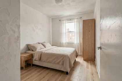 Chambre de 12x12 pieds bien aménagée avec lit queen, parquet clair et décoration minimaliste
